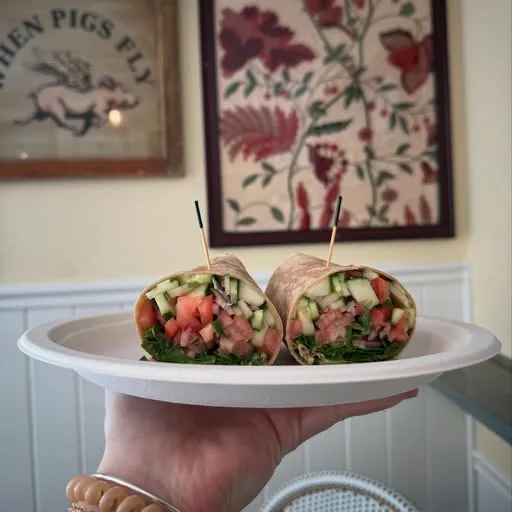 A salad wrap cut in half and stood up on a paper plate